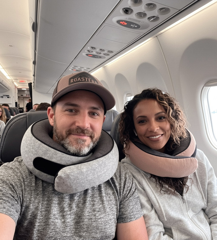 Two travelers wearing gray and pink Avemos neck pillows on an airplane